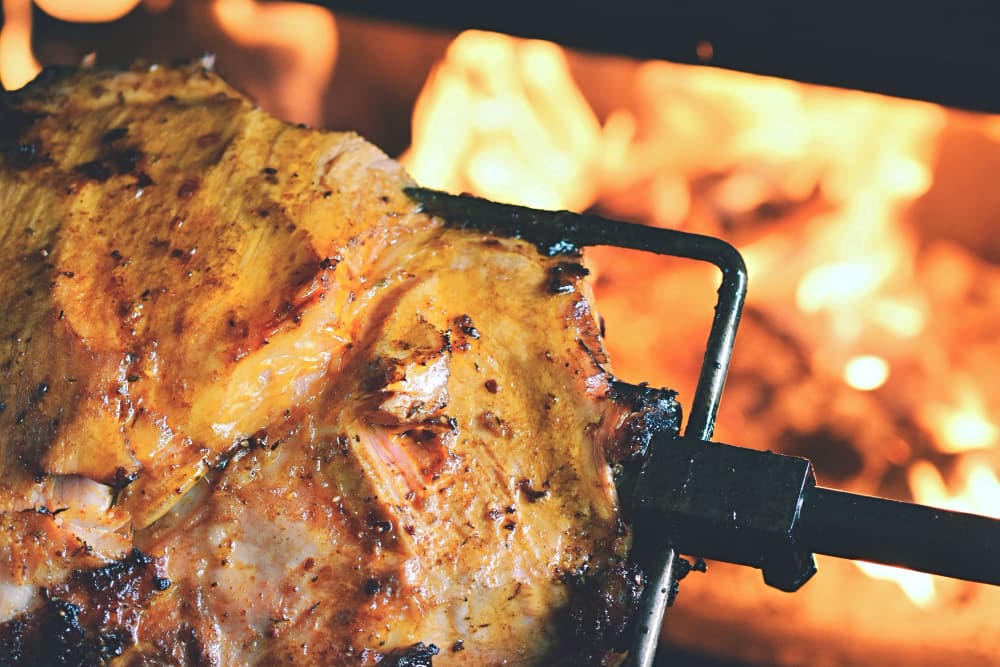 Outdoor spit braai barbecue with meat and vegetables grilling